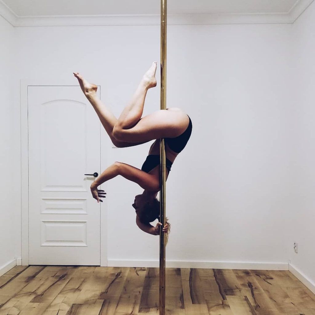 Alumna practicando una figura básica de Pole Fitness en una barra vertical en estudio de Granada.