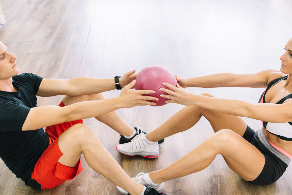 Persona realizando ejercicios de Pilates suelo con pelota pequeña en un estudio luminoso de Granada.